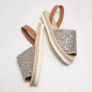 Close-up of sparkly glitter peep-toe sandals with tan straps and espadrille sole