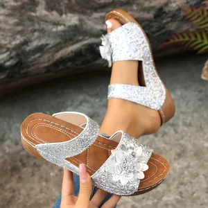 Detail view of silver glitter wedge sandals with decorative flower and textured sole