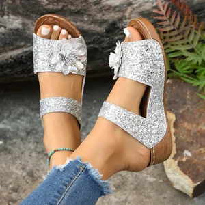 Close-up detail of silver glitter wedge sandals featuring elegant 3D flower decor