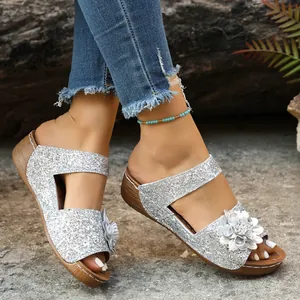 Detailed view of silver glitter wedge slippers featuring a decorative floral applique