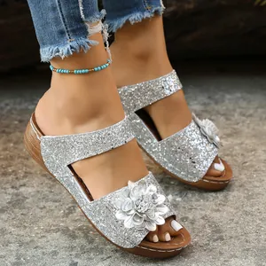 Close-up of silver glitter wedge sandals featuring a delicate 3D flower on the strap.