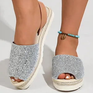 Close-up detail of silver glitter peep-toe sandals featuring a woven platform sole