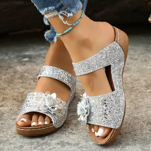 Detailed shot of silver glitter wedge sandals featuring a stylish 3D flower accent.