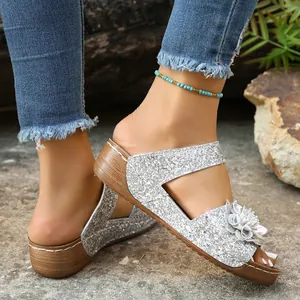 Detail shot of silver glitter straps and decorative leather flower on wedge sandals