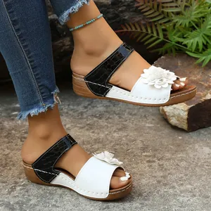 Detail view of women's wedge sandals with white floral embellishment and crocodile pattern