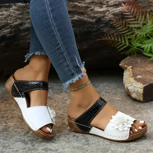 Detailed view of women's wedge sandals featuring flower accent and crocodile pattern