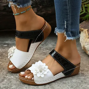 Detailed view of women's wedge sandals featuring a white flower and black crocodile strap