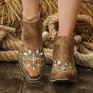 Macro view of vintage brown western ankle boots featuring floral embroidery and bronze rivets