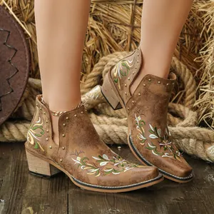 Detailed view of vintage brown western ankle boots with floral embroidery and gold studs