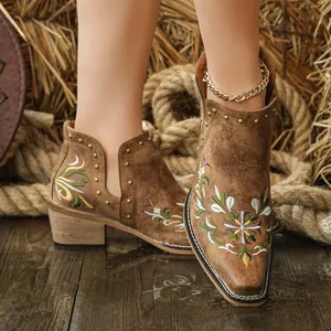 Close-up of retro women's western ankle boots with floral embroidery and rivets.
