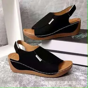 Close-up detail of women's black wedge sandals featuring fashionable labels and thick soles