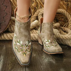 Detailed view of embroidered western ankle boots with bronze rivets and floral motifs