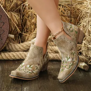 Detail of vintage Western ankle boots with floral embroidery and gold rivets
