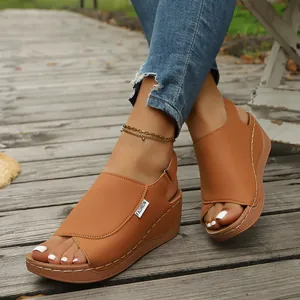 Detailed close-up of brown faux leather wedge sandals with white decorative stitching