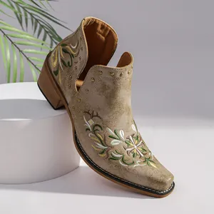 Detailed view of ethnic embroidered Western ankle boots with gold studs and chunky heel.