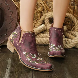 Detailed view of vintage burgundy western boots featuring floral embroidery and gold rivets