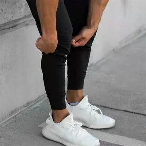 Close-up of men's tapered athletic joggers in black cotton blend fabric with elastic cuffs