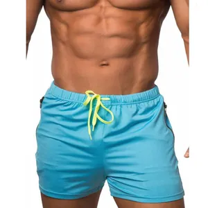 Detalle de pantalones cortos deportivos azules para hombre con cordón amarillo neón y cremallera
