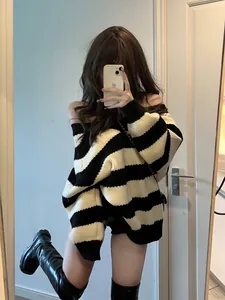 Oversized black and white striped knit sweater worn with black boots for a chic look