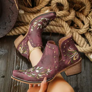 Close-up of vintage wine red western boots with floral embroidery and studs