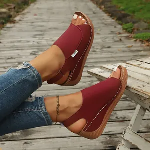 Detailed view of wine red wedge sandals featuring white stitching and fashion side tag