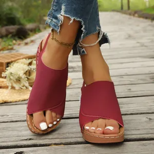 Detailed close-up of wine red wedge sandals featuring a thick sole on a wooden path