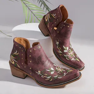 Side-on detail of burgundy vintage Western boots with floral embroidery and studs