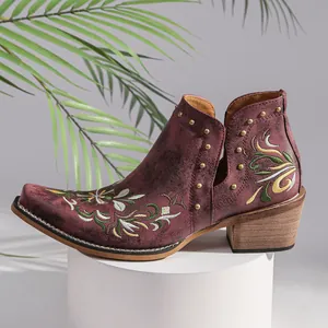 Close-up detail of burgundy Western ankle boots with floral embroidery and gold studs