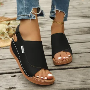 Detail shot of black wedge sandals with white stitching and fashionable open-toe design.