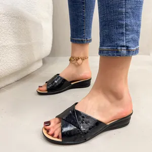 Close-up of black cross-strap wedge slides with shiny textured finish for women