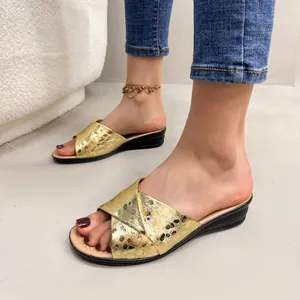 Detailed view of gold metallic wedge sandals worn with denim for a stylish look