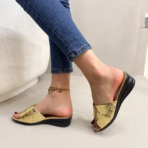 On-feet view of gold metallic wedge sandals with textured straps and black soles.