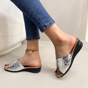 Side view of silver metallic wedge sandals with textured cross straps on a model