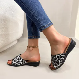 Close-up of leopard print wedge sandals worn with blue jeans and anklet