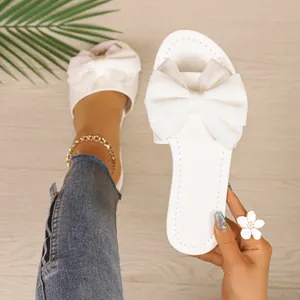 Vista detallada de elegantes chanclas blancas con un gran lazo decorativo de tela