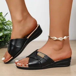 Detailed shot showing the black faux leather wedge sandals with rhinestone buckle.
