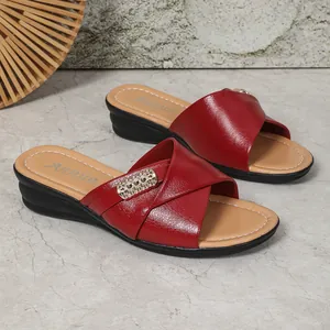 Close-up of red wedge sandals for women with criss-cross straps and shiny metallic buckle