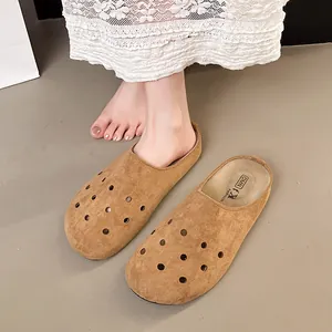 Dettaglio dei sabot eleganti in camoscio marrone con fori decorativi e suola piatta