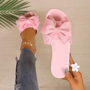 Detalle de alta calidad de sandalias planas rosas con un elegante lazo de tela grande