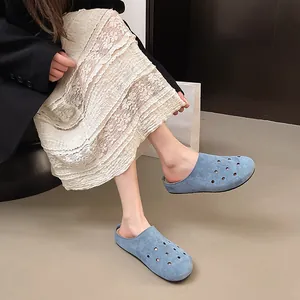 Sabot chiusi blu con fori circolari decorativi indossati da una donna con gonna