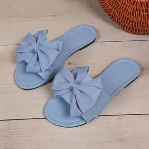 Primer plano de sandalias planas azul claro con un gran lazo decorativo suave