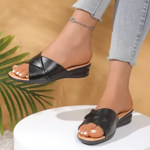 Detail view of black wedge sandals with crossover straps and open-toe design