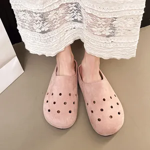 Primo piano di zoccoli in pelle scamosciata rosa traforati con design slip-on da donna