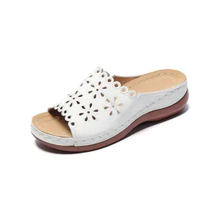 Side view of white women's wedge slippers with laser-cut floral pattern detailing
