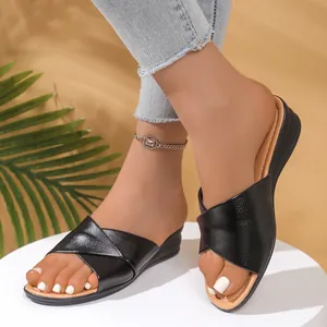 Close-up view of black cross-strap wedge sandals worn on a model's feet