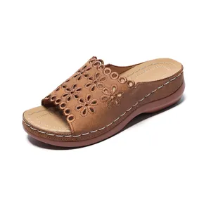 Close-up of brown women's wedge sandals with laser-cut flower pattern and white stitching.