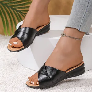 Detailed view of fashionable black cross-strap wedge sandals for women worn on feet