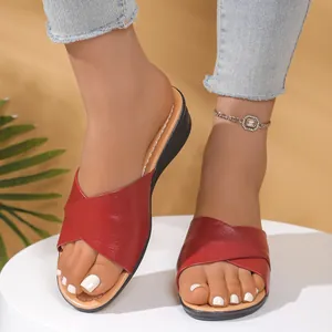 Close-up of red criss-cross strap wedge sandals for women on a white pedestal