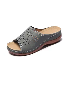 Detail view of grey wedge sandals with decorative floral cutout pattern and stitching.