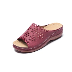 Detail view of maroon peep-toe wedge sandals with decorative laser-cut floral designs.